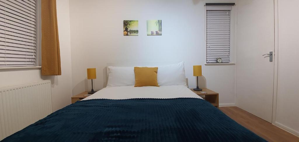 - une chambre avec un lit avec une couverture bleue et 2 lampes dans l'établissement Kingsley House, à Hastings