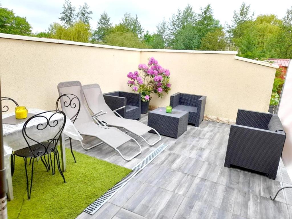 un patio con sillas, una mesa y flores en Maison d'une chambre avec jardin clos et wifi a Brevonnes, en Brévonnes