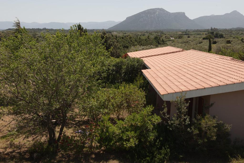 une maison avec un toit rouge, des arbres et des montagnes dans l'établissement Agriturismo Don Lucifero, à Orosei