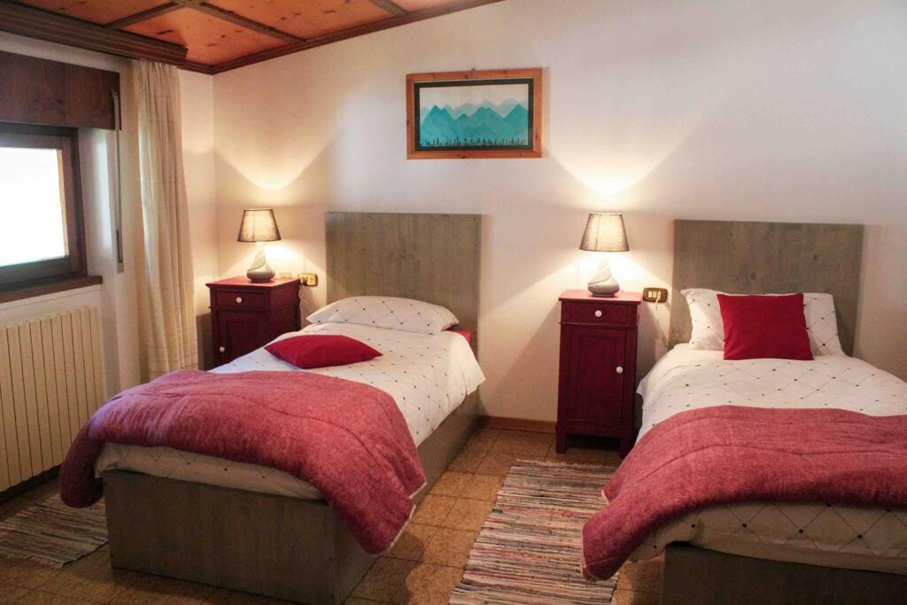 1 dormitorio con 2 camas con sábanas rojas y blancas en All'Ombra del Mortirolo, en Mazzo di Valtellina