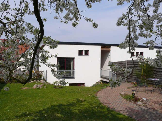 a white house with a tree and a grass yard at Ferienwohnungen "Vieling" Objekt-ID 12155-9 in Waren