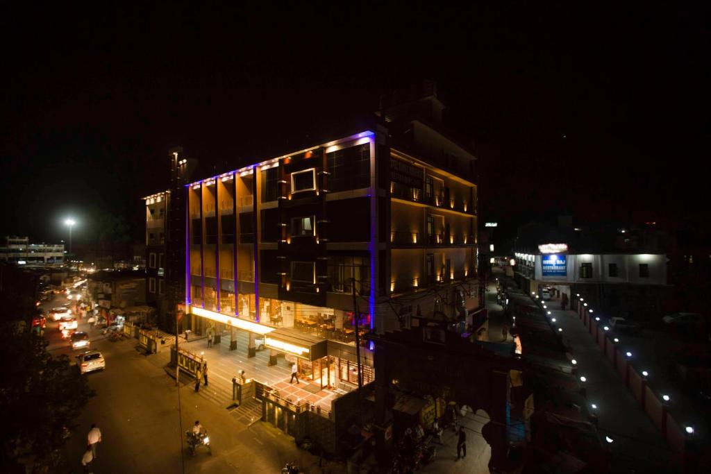 un edificio con luces púrpuras en una calle de la ciudad por la noche en Hotel Kings Regency, en Drang