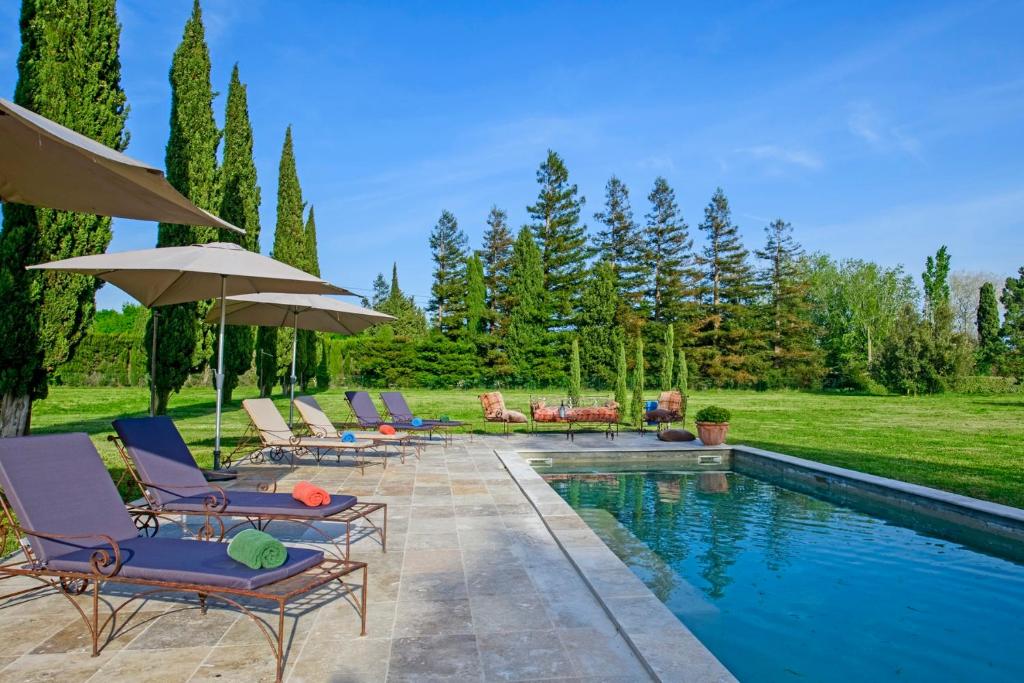 a group of chairs and umbrellas next to a swimming pool at Bastide de Bellegarde in Avignon