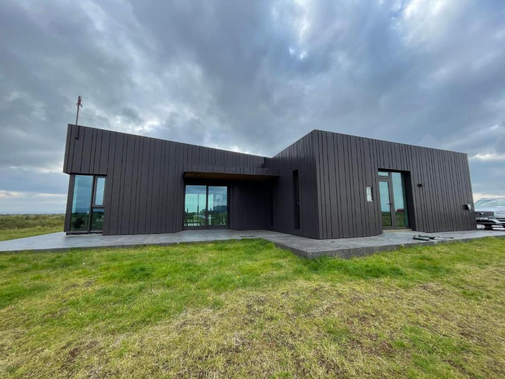 un edificio negro con puertas de cristal en un campo de césped en Fögruvellir Country House, en Hella