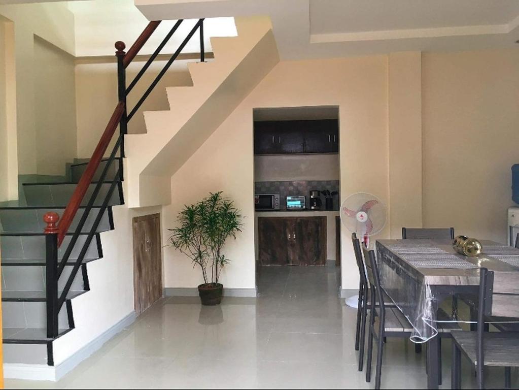 a living room with a staircase and a dining table at Kylitas transient house- Bohol in Tagbilaran City