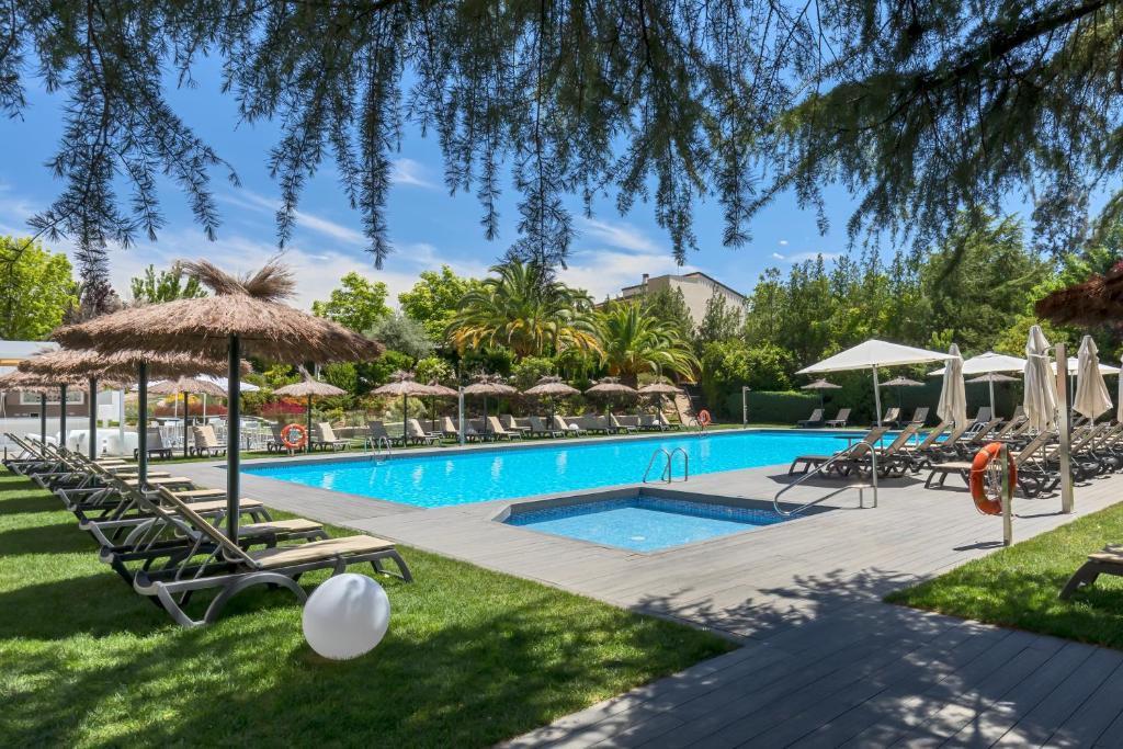 una piscina con tumbonas y sombrillas en Barceló Cáceres V Centenario, en Cáceres