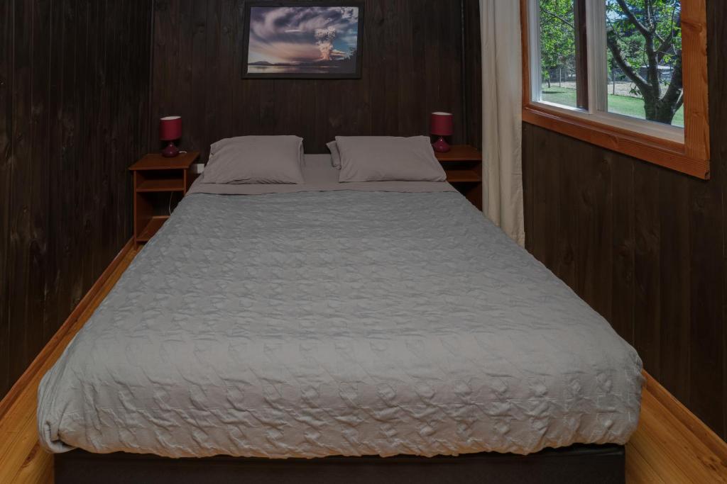 a large bed in a small room with a window at Bordemundo B&B y Cabañas in Puerto Varas