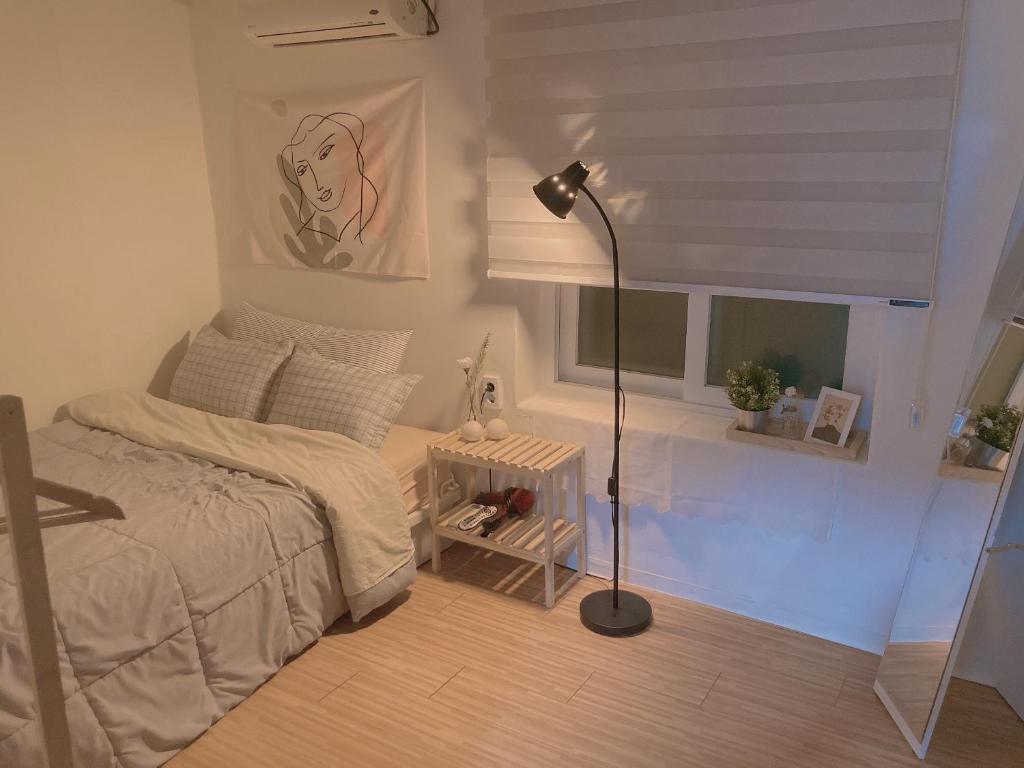 1 dormitorio con cama, lámpara y ventana en Yakorea Hostel Dongdaemun, en Seúl