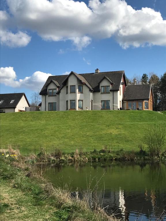 a large house on a grassy hill with a pond at Druid View B&B in Inverness