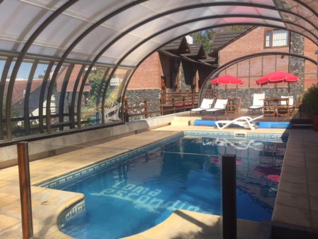 una piscina en un edificio con un arco en Loma Escondida Apart Cabañas & Spa en Villa Gesell