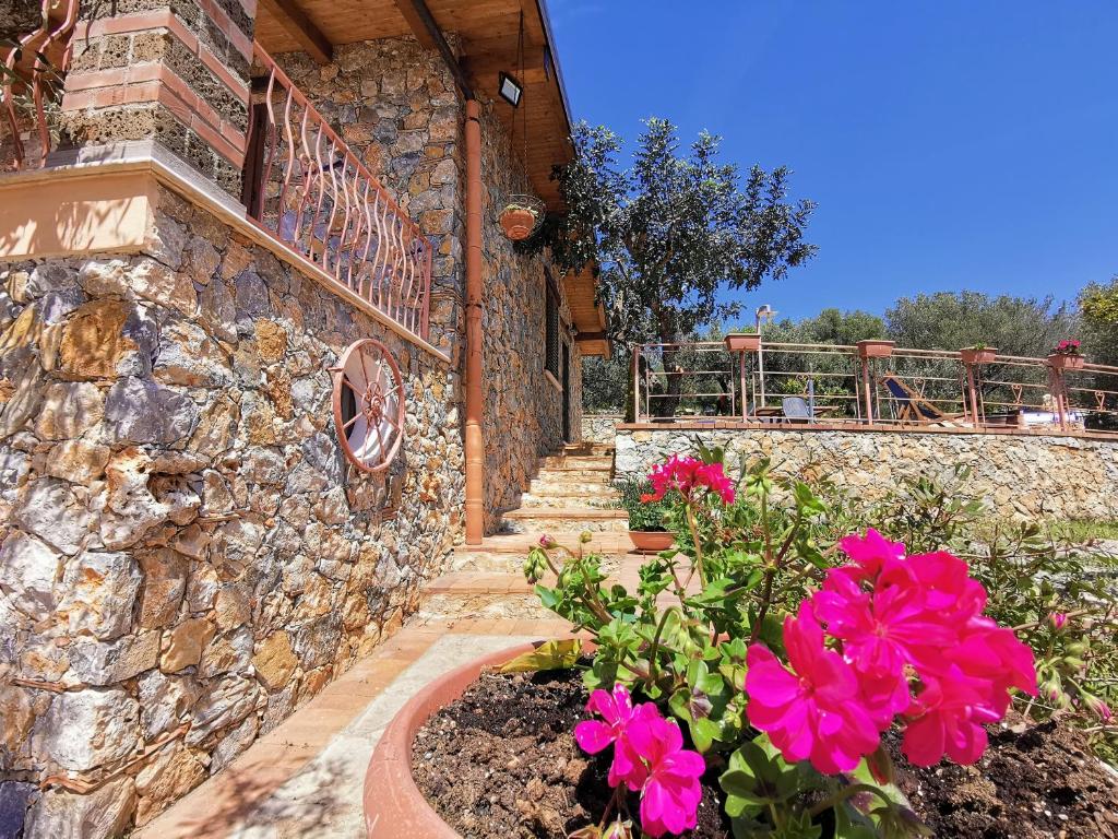 un edificio de piedra con escaleras y flores rosas en Villetta Starza, en Marina di Camerota