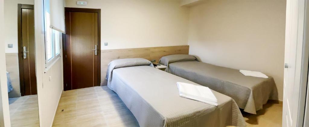 una habitación de hospital con 2 camas y una puerta en Hostal Restaurante Cuatro Caminos, en Cubillos del Sil
