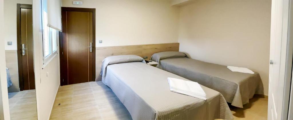 a hospital room with two beds and a door at Hostal Restaurante Cuatro Caminos in Cubillos del Sil