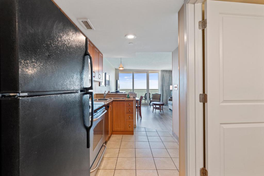 a kitchen with a black refrigerator and a dining room at Sandy Beach Resort in Myrtle Beach