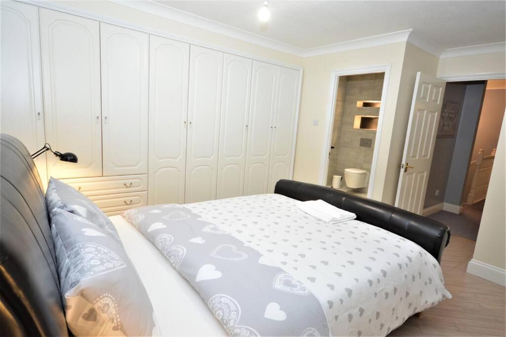 a bedroom with a bed with a white bedspread at Luxury 5 Bedroom House with Free Parking on Site in Hornchurch