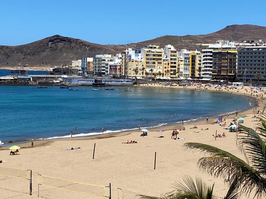 un gruppo di persone su una spiaggia vicino all'acqua di Las Canteras beach and sea, wifi, terraza, comodidad a Las Palmas de Gran Canaria