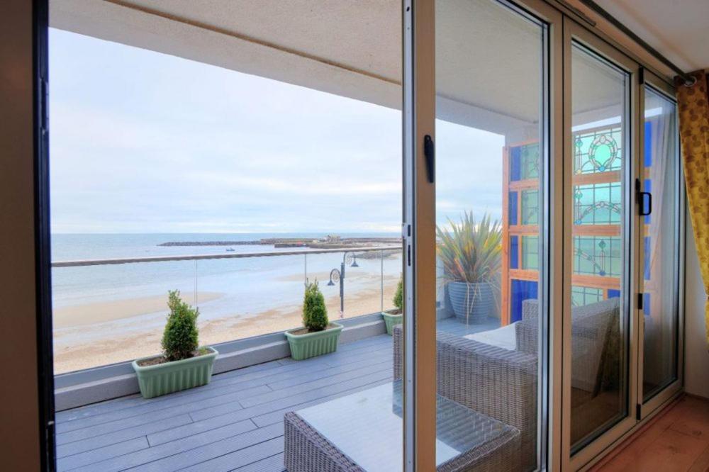 a balcony with a view of the beach at Largigi offering two amazing panoramic sea front apartments in Lyme Regis