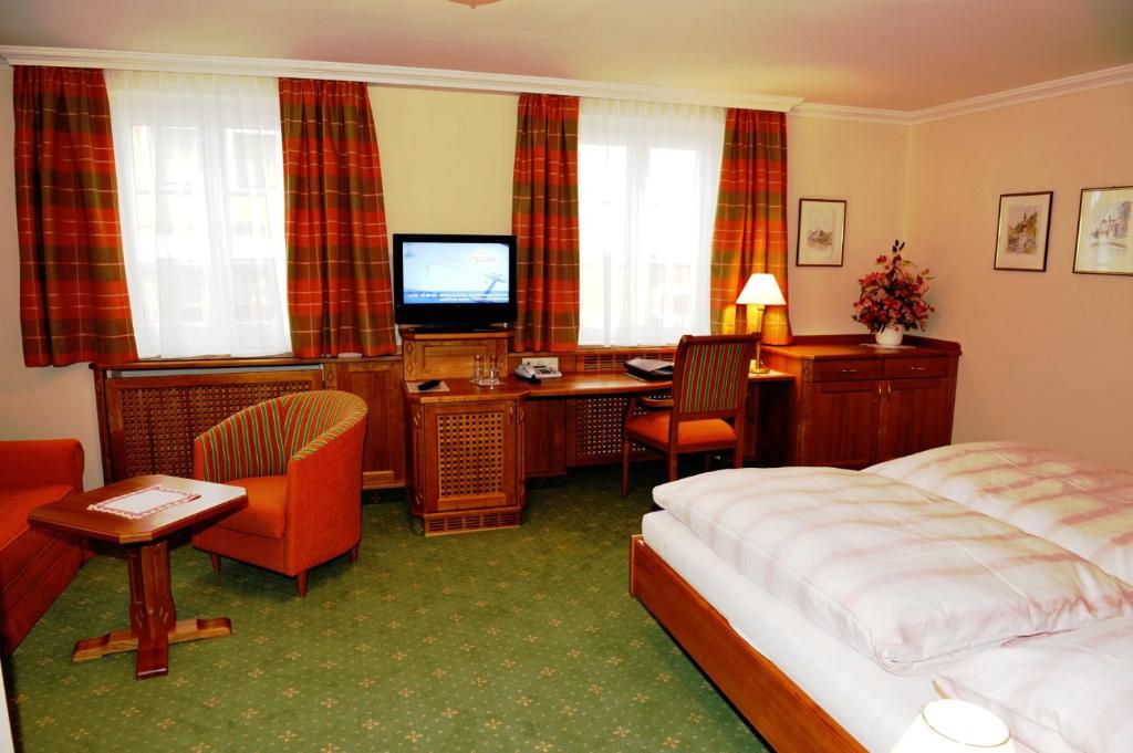 a hotel room with a bed and a desk and a television at Pension Hochleitner am Schloßpark in Tamsweg