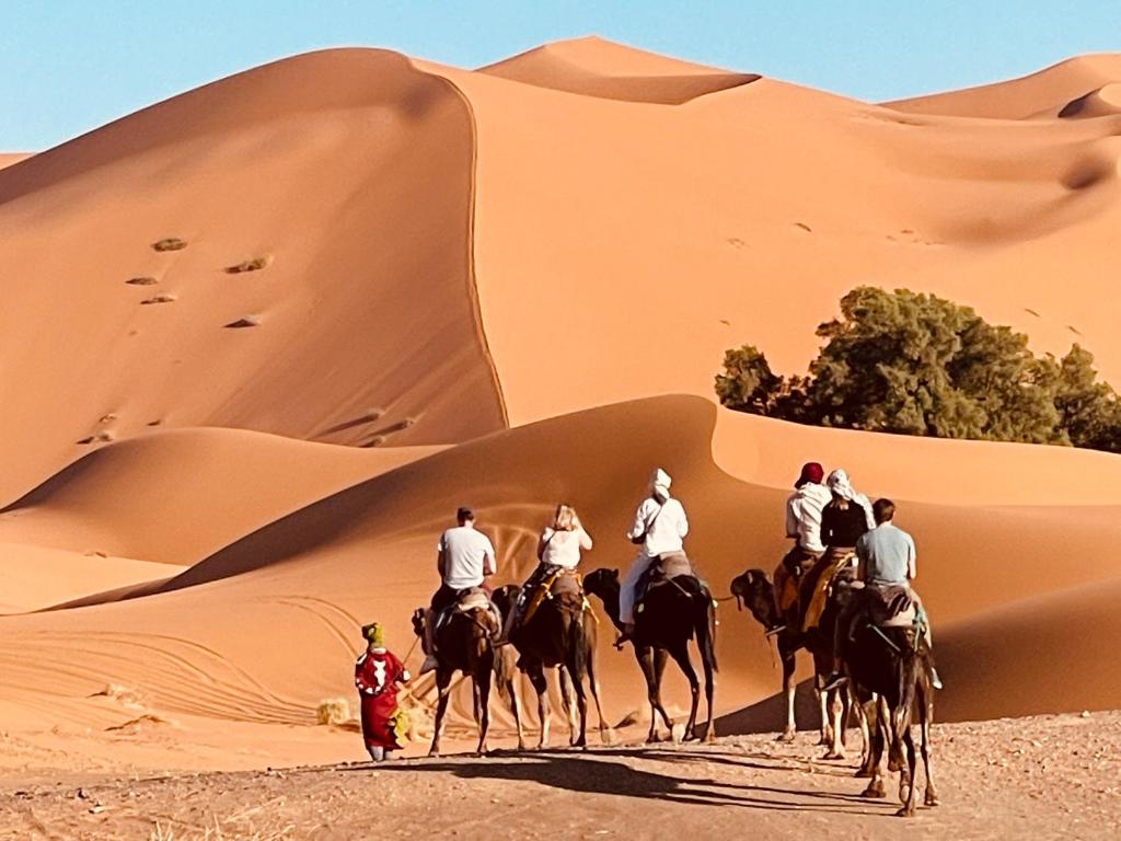 Un gruppo di persone che cavalcano nel deserto di Sahara Nomad Camp a Merzouga