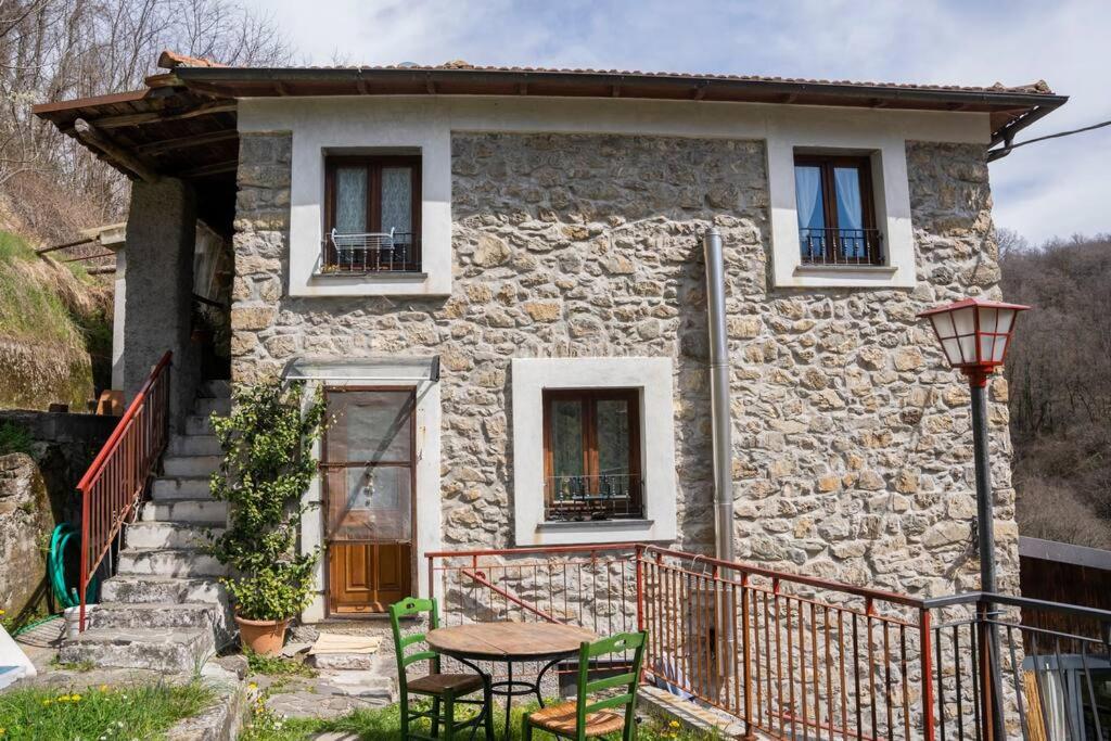 una pequeña casa de piedra con una mesa delante en 036 - La Casa di PIETRA Maissana Relax e Natura, en Chiama