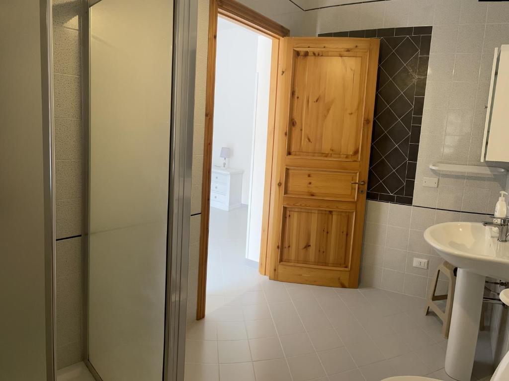 bagno con porta in legno e lavandino di B&B La CYCAS a San Vito lo Capo