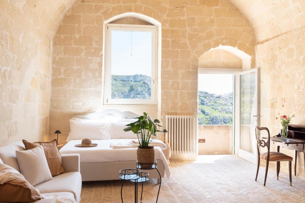 a bedroom with a bed and a couch and a table at Suite Santa Maria - L'Opera Dell'Architetto in Matera