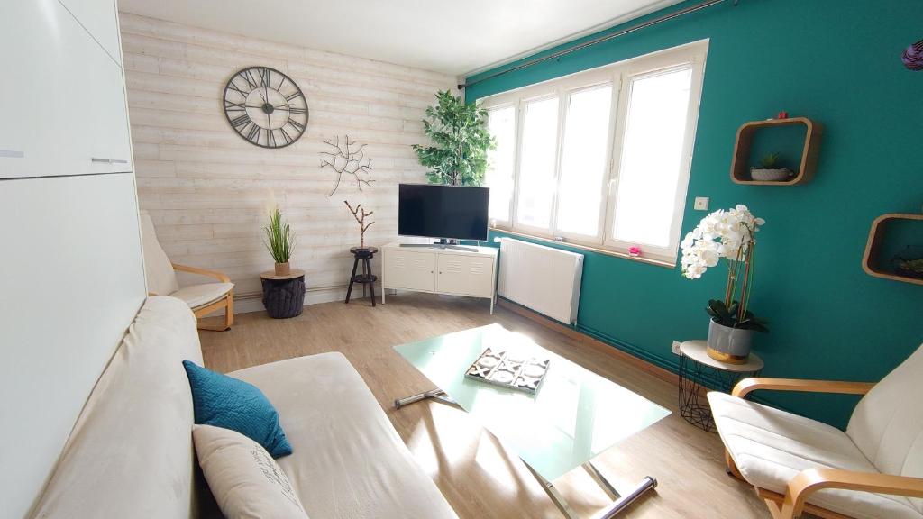 uma sala de estar com um sofá e uma televisão em LE JADE em Saint-Nazaire