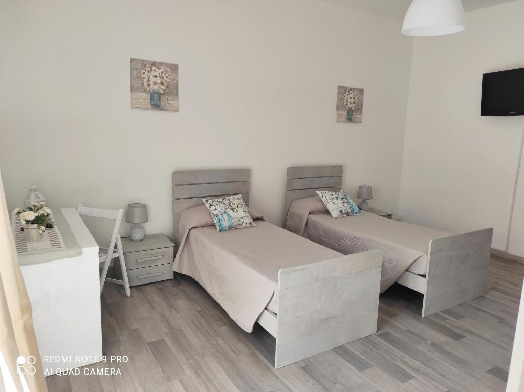 1 dormitorio con 2 camas, escritorio y TV en Alcivico26 en Alghero