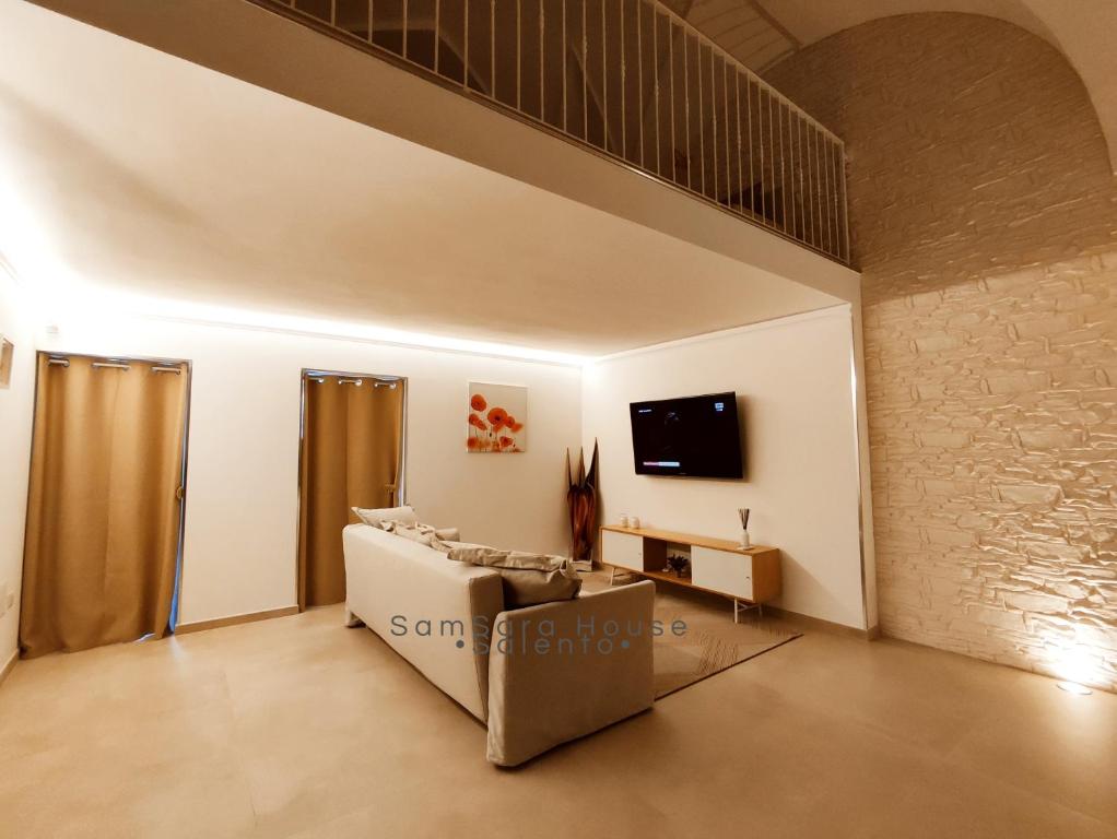 ein Wohnzimmer mit einem Sofa und einem TV an der Wand in der Unterkunft SamSaraHouse Salento in Felline