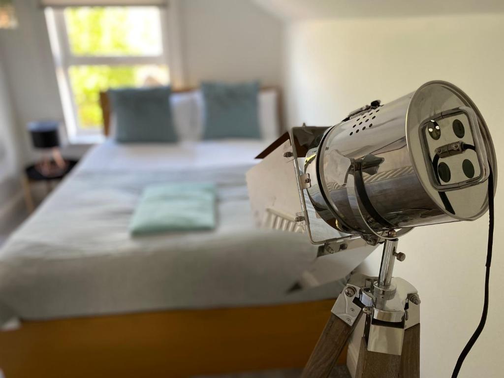 a light on a tripod next to a bed at Tudor House Gloucester by StayStaycations in Gloucester