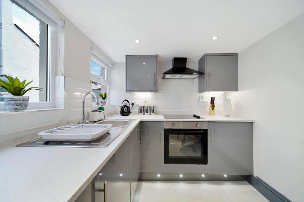 a white kitchen with a sink and a window at Magee Town House 'Sleeping 8 guests' in Londonderry County Borough