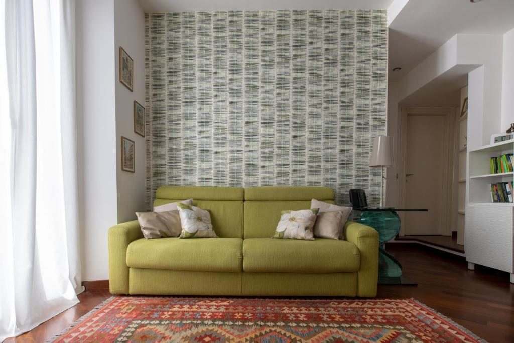 um sofá verde numa sala de estar com um tapete em Madeleine apartments - Residenza Belle Époque em Milão