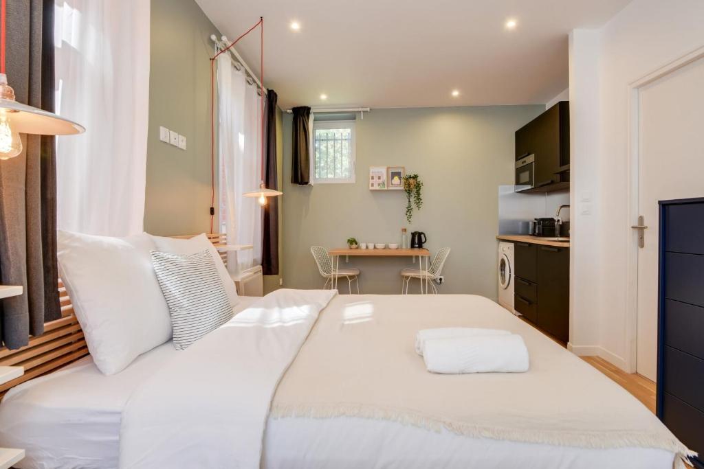 Cette petite chambre comprend un grand lit blanc et une table. dans l'établissement Lille Centre - Nice studio, à Lille