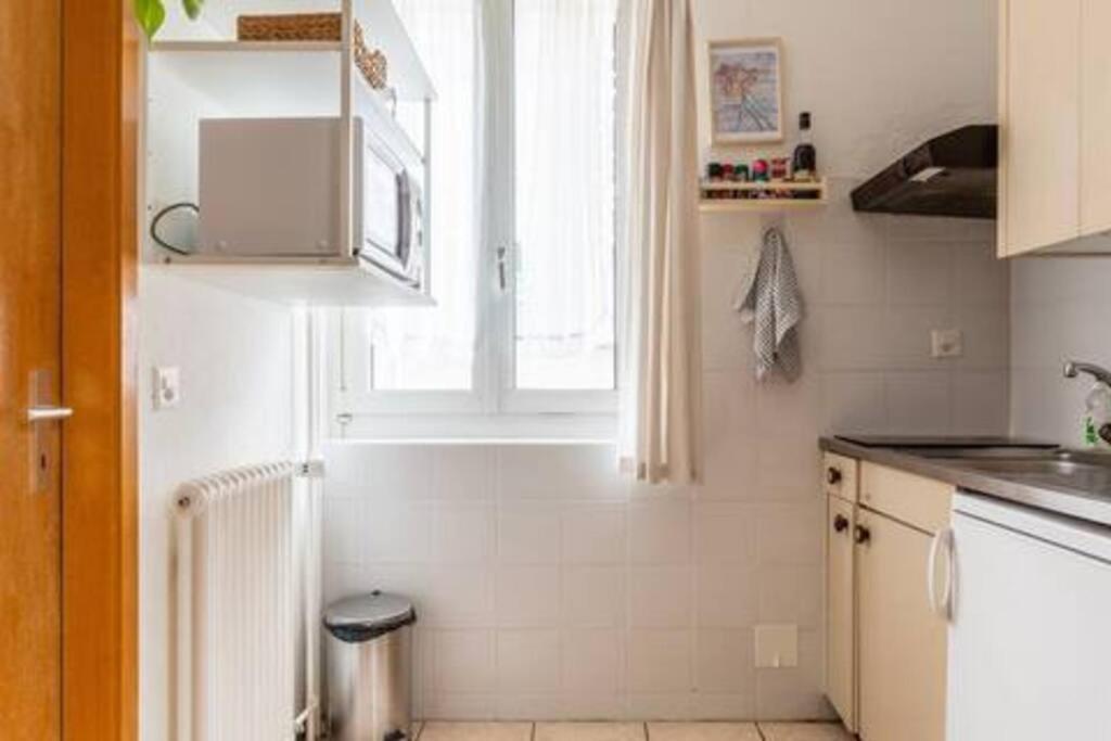 uma pequena cozinha com uma janela e um lavatório em Cosy em Lausanne