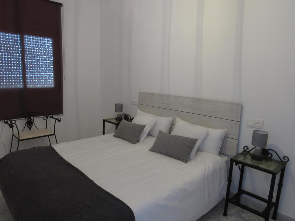 um quarto com uma grande cama branca e 2 almofadas em CASA TITO JOSE em Valle de Abdalagís