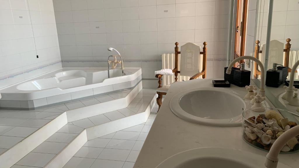 a white bathroom with a tub and a sink at Brezza Affittacamere in Montemarciano