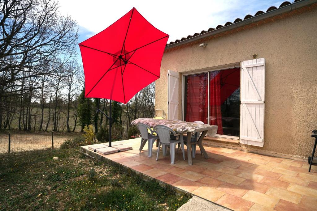 a table and chairs with a red umbrella on a patio at Loft avec mezzanine in Montagnac