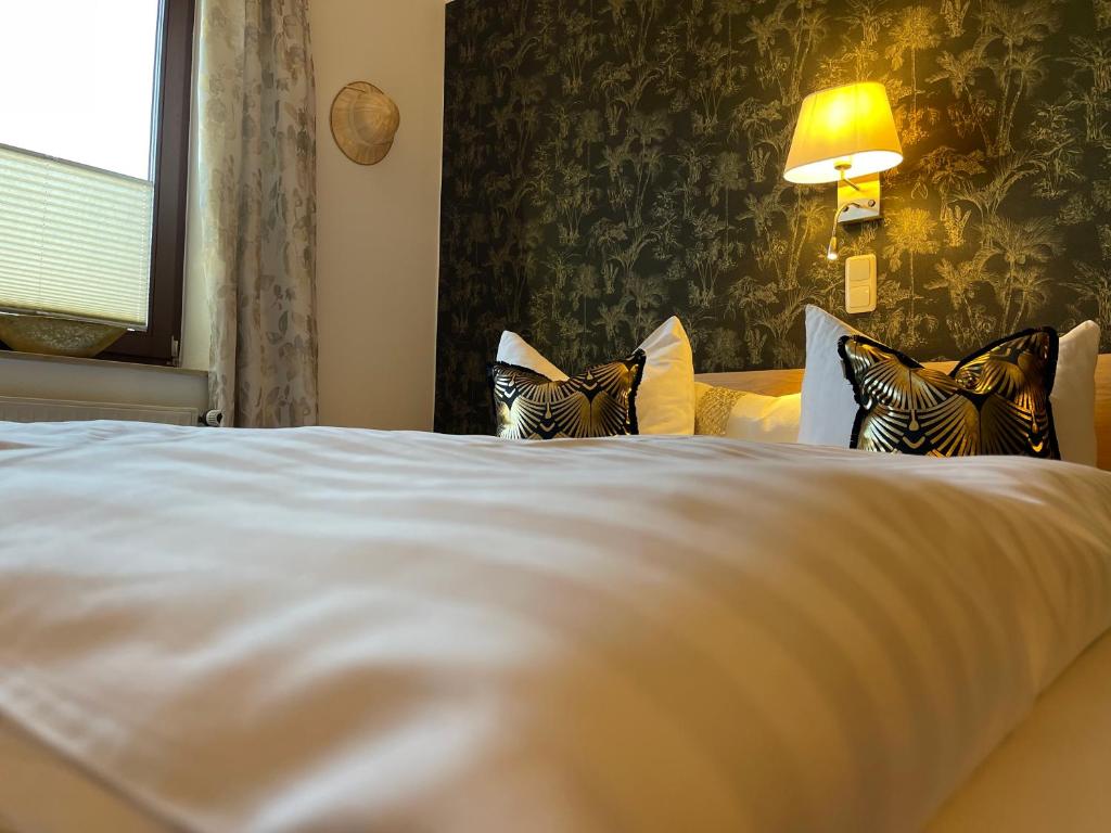 1 dormitorio con 1 cama blanca con lámpara y ventana en Freigeist • Pension & Brasserie en Witzin