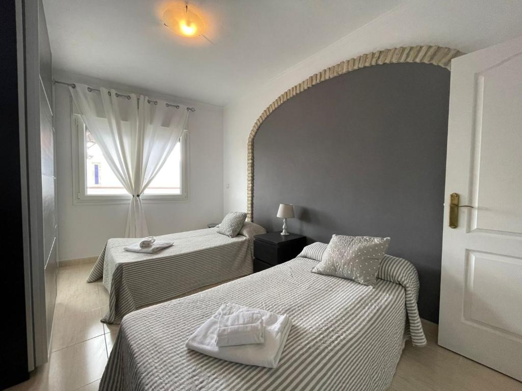 Cette chambre comprend 2 lits et une fenêtre. dans l'établissement Aires de Regla, Apartamentos Living Sur, à Chipiona