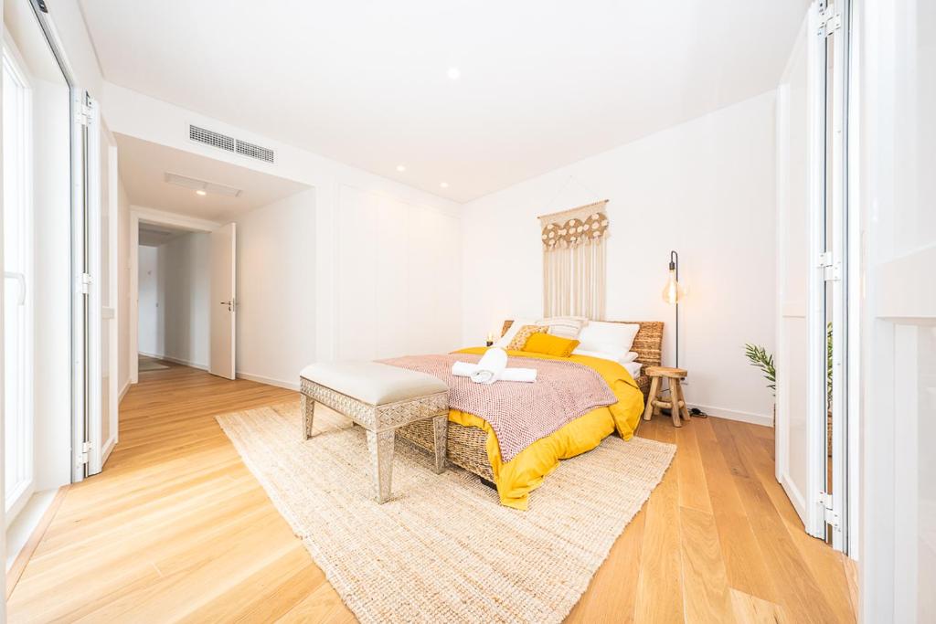 a white bedroom with a bed and a rug at Apartamento situado no centro histórico da cidade in Setúbal