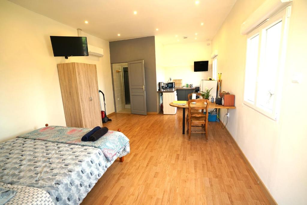 a bedroom with a bed and a table and a kitchen at Studio Indépendant Douceur Provençale in Montagnac