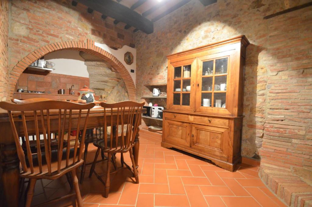 a kitchen with a wooden table and a brick wall at La Divina Dimora Il Castello degli Spiriti Magni in Montepescali