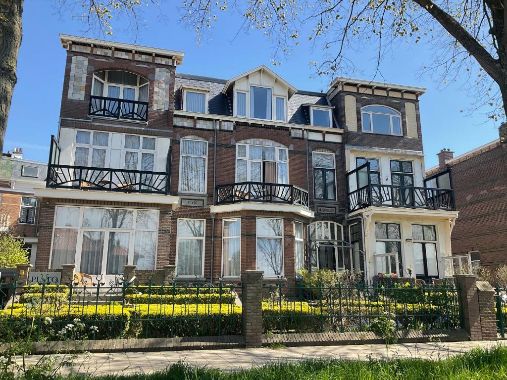 une grande maison en briques brunes avec des fenêtres blanches dans l'établissement Plato by Hofstad Studio’s, à Scheveningen