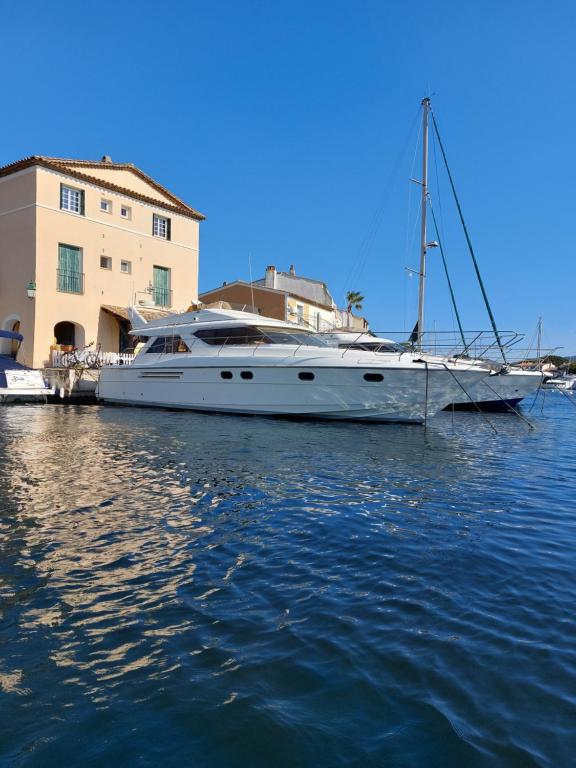 un bateau blanc assis dans l'eau à côté d'un bâtiment dans l'établissement ENERGY Rêves D'Ô, à Grimaud