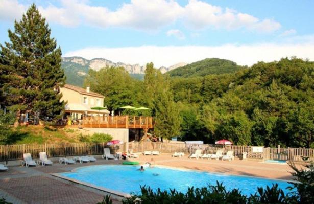 une grande piscine avec des chaises longues et une maison dans l'établissement Camping Le Gallo Romain, à Barbières