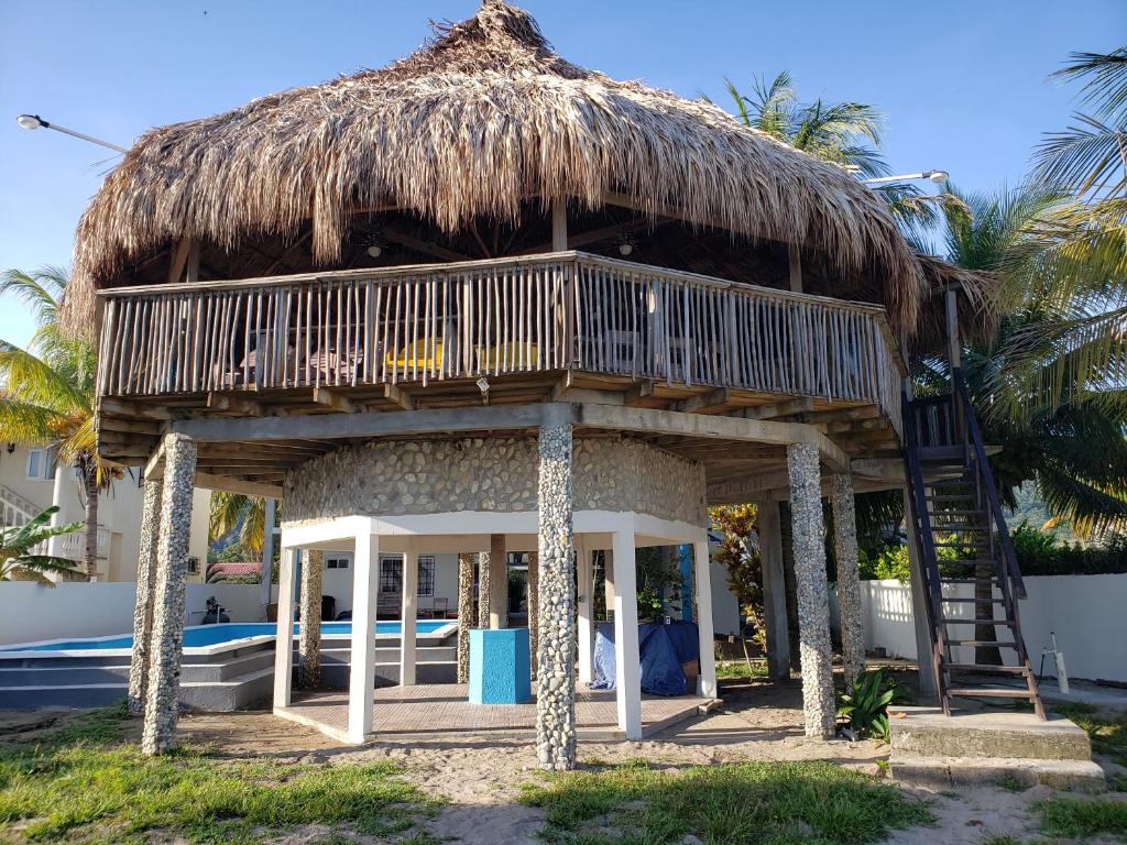 a hut with a thatched roof on a beach at Paradise Found in La Ceiba