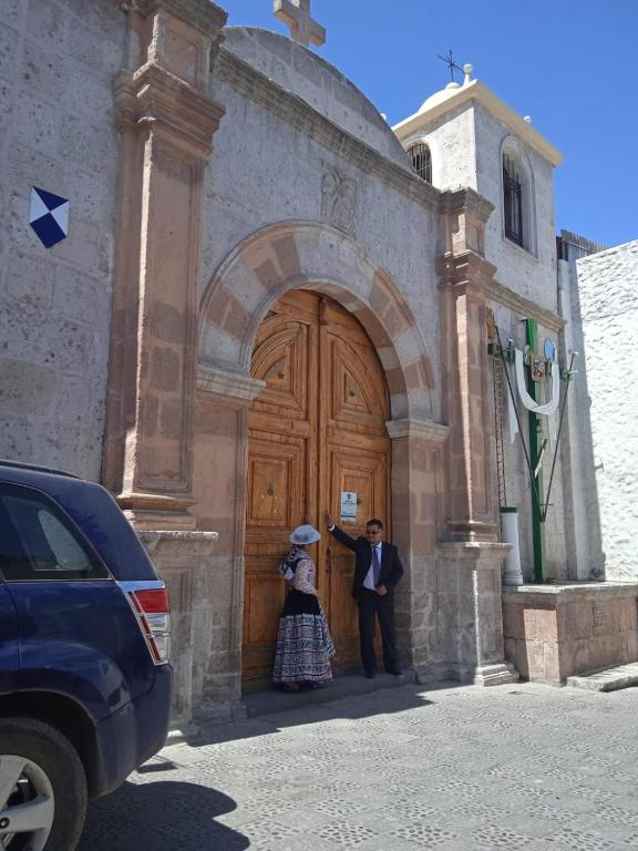 a man and a woman standing in front of a church at la casa de los amigos in Arequipa