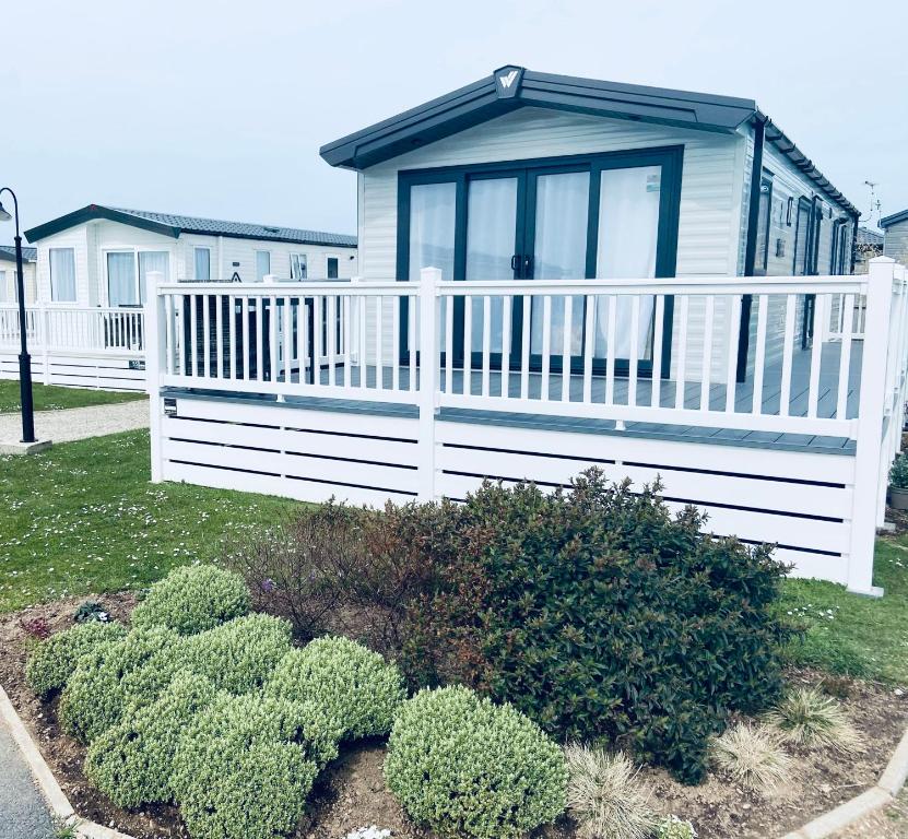 uma casa com uma cerca branca e alguns arbustos em new Perran holiday resort em Newquay