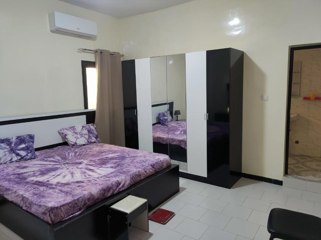 1 Schlafzimmer mit 2 Betten und einem Spiegel in der Unterkunft Gassimmo Avril Location d'appartements in Thiès