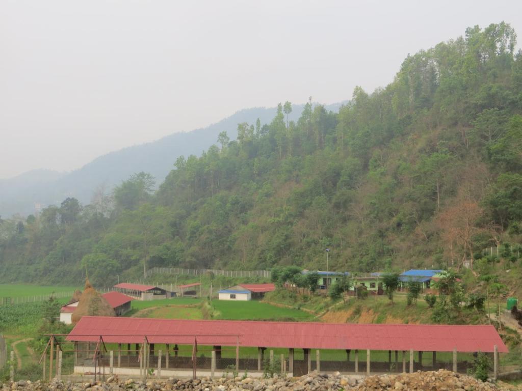a small village on a hill with a red roof at Gorkha Organic Agro Farm in Gorkhā